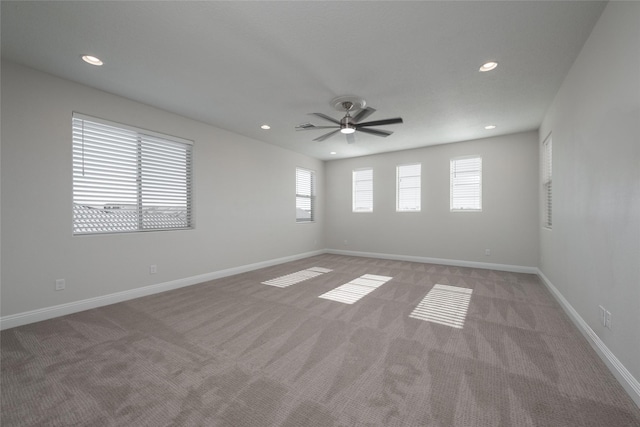 carpeted spare room featuring ceiling fan and a wealth of natural light