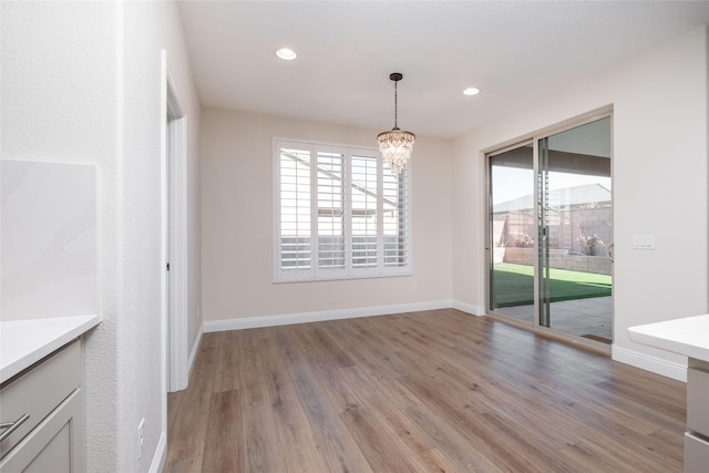 unfurnished dining area with a chandelier and light wood-type flooring