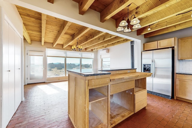 kitchen with tasteful backsplash, hanging light fixtures, light brown cabinets, stainless steel fridge, and a notable chandelier