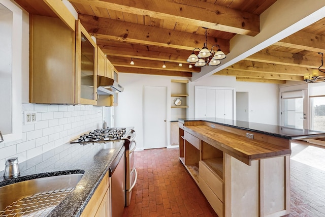 kitchen with sink, gas range, a center island, beamed ceiling, and backsplash