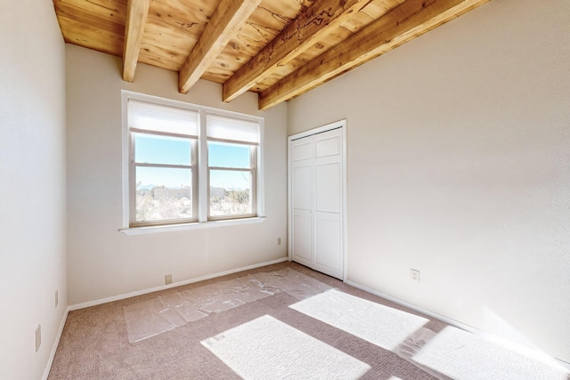 unfurnished bedroom featuring beamed ceiling, a closet, light carpet, and wooden ceiling