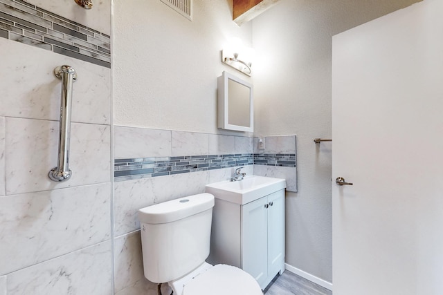 bathroom with vanity, tile walls, and toilet