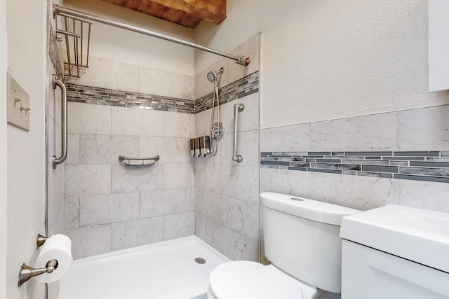 bathroom featuring a tile shower, tile walls, vanity, and toilet