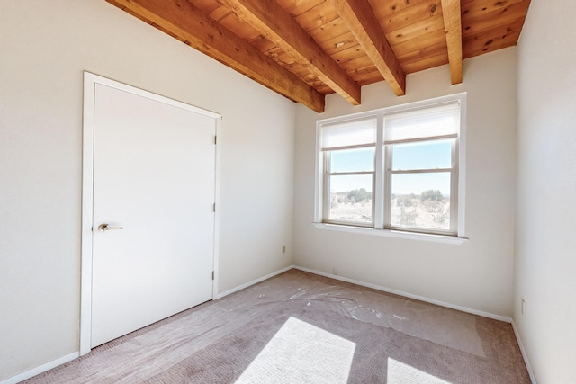 empty room with beamed ceiling, light colored carpet, and wood ceiling