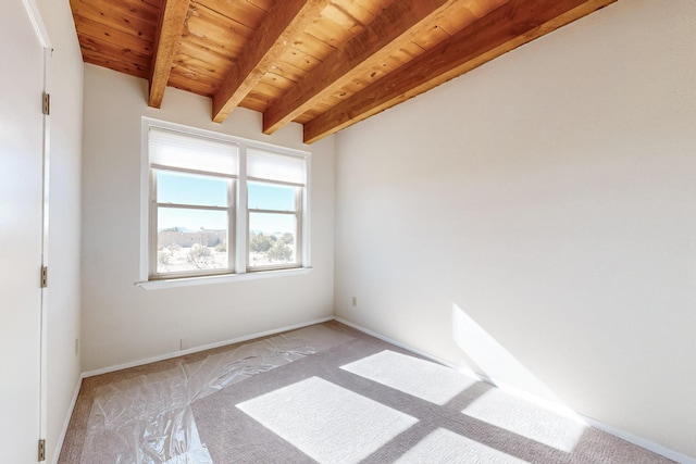 carpeted empty room with beamed ceiling and wooden ceiling