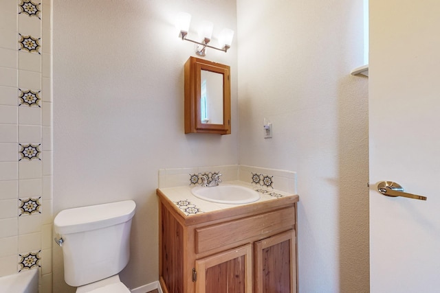 bathroom with vanity, a tub to relax in, and toilet