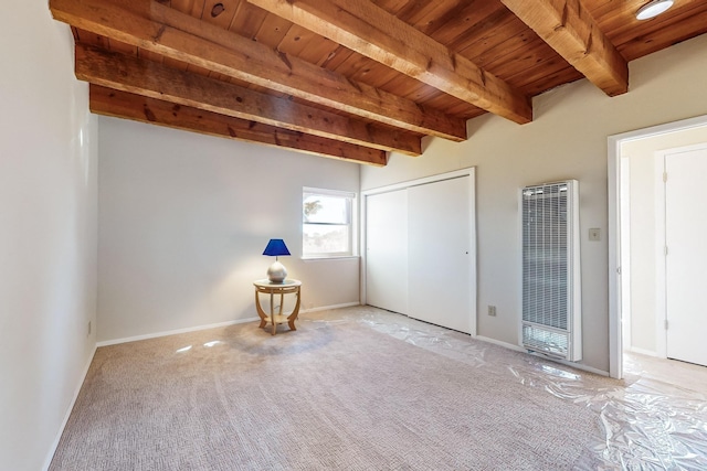 spare room featuring beam ceiling, light colored carpet, and wooden ceiling