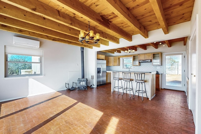 kitchen with beamed ceiling, a wall mounted AC, a breakfast bar area, a center island, and stainless steel fridge with ice dispenser