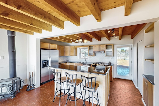 kitchen featuring sink, appliances with stainless steel finishes, a kitchen island, beam ceiling, and backsplash