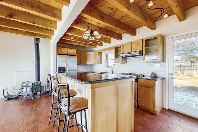 kitchen featuring pendant lighting, decorative backsplash, a center island, stainless steel appliances, and beam ceiling