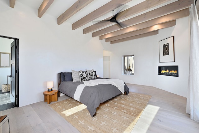 bedroom with light hardwood / wood-style floors and beamed ceiling