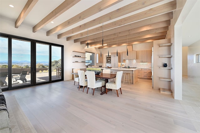 dining space featuring beamed ceiling, sink, and light hardwood / wood-style floors