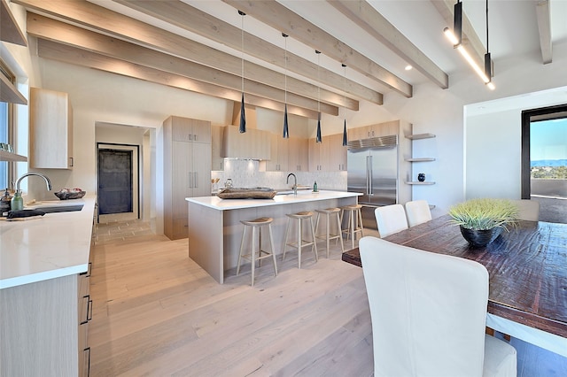 dining room with sink, beam ceiling, and light hardwood / wood-style floors