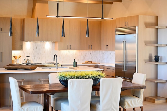 kitchen with built in fridge, pendant lighting, tasteful backsplash, sink, and light brown cabinets