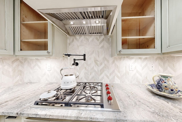 kitchen featuring premium range hood, light stone countertops, stainless steel gas cooktop, and decorative backsplash