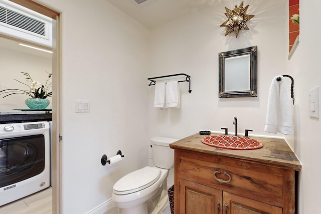 bathroom featuring hardwood / wood-style flooring, vanity, toilet, and washer / dryer