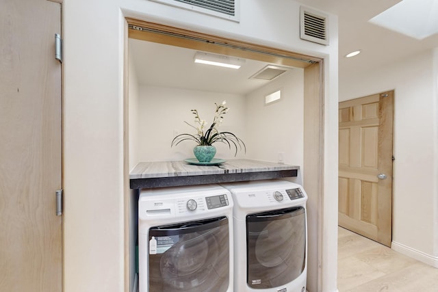 clothes washing area featuring independent washer and dryer and light hardwood / wood-style flooring