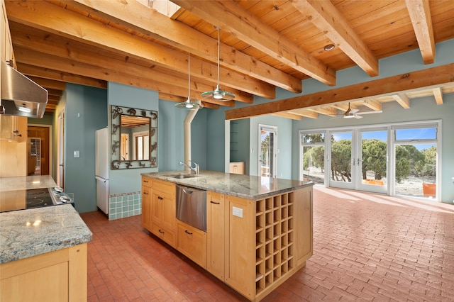 kitchen with pendant lighting, light brown cabinetry, sink, light stone countertops, and a center island with sink