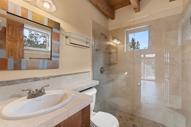 bathroom with a tile shower, vanity, tasteful backsplash, toilet, and beamed ceiling