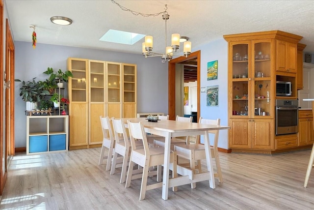 dining room with a chandelier, a textured ceiling, and light wood-type flooring