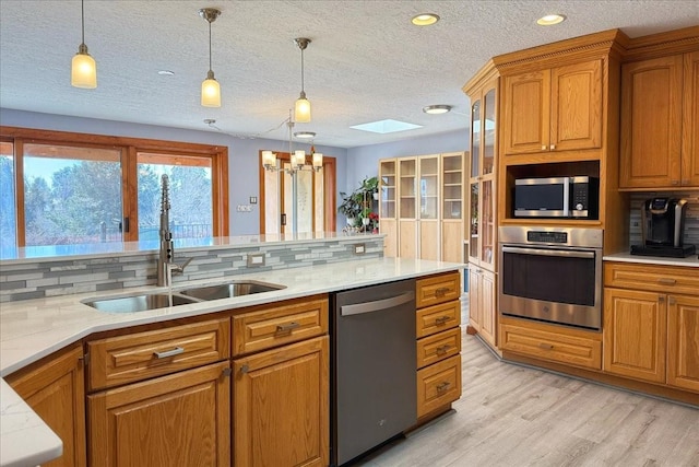 kitchen featuring stainless steel appliances, sink, backsplash, and decorative light fixtures