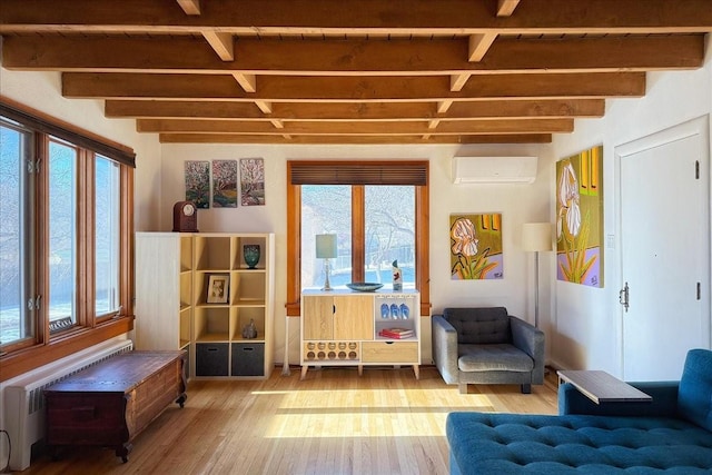 living area with wood-type flooring, a wall unit AC, and beamed ceiling