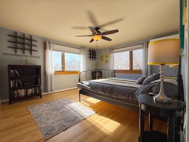 bedroom with multiple windows, ceiling fan, and light hardwood / wood-style flooring