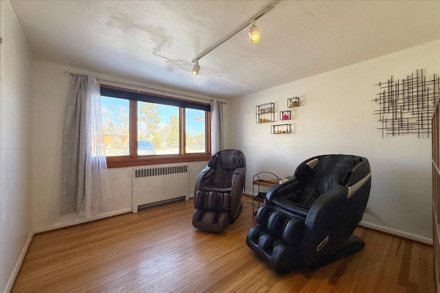 living area with hardwood / wood-style flooring, rail lighting, radiator, and a textured ceiling