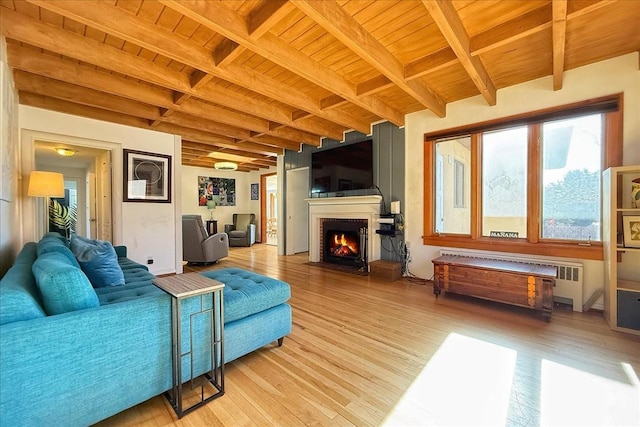 living room with radiator, hardwood / wood-style floors, beam ceiling, a fireplace, and wooden ceiling