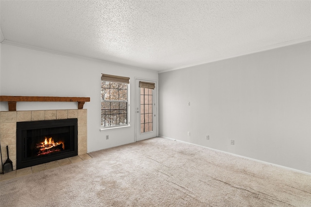 unfurnished living room with a tiled fireplace, crown molding, light colored carpet, and a textured ceiling