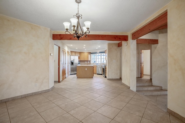 kitchen with stainless steel appliances, a center island, light tile patterned flooring, decorative light fixtures, and beamed ceiling