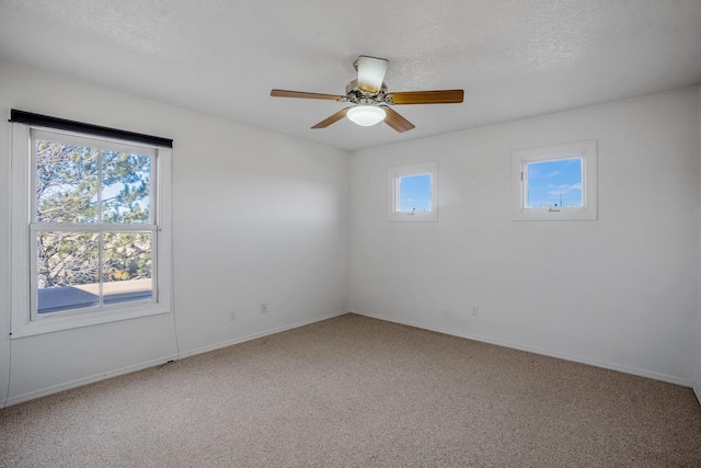 carpeted spare room with ceiling fan, a healthy amount of sunlight, and a textured ceiling