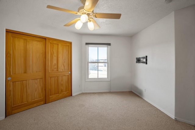 unfurnished bedroom featuring ceiling fan, light carpet, and a textured ceiling