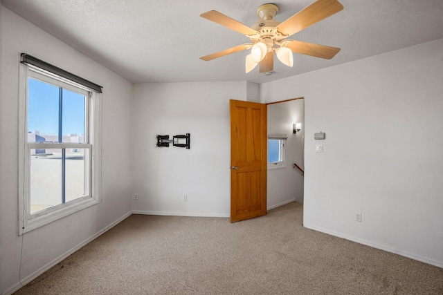 carpeted spare room with ceiling fan and a textured ceiling