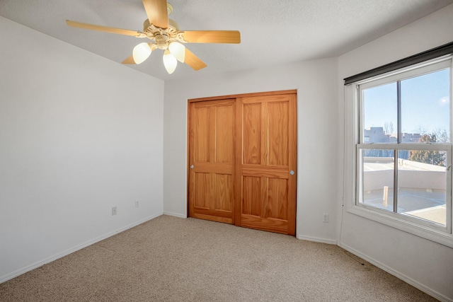 unfurnished bedroom with light carpet, a textured ceiling, and ceiling fan