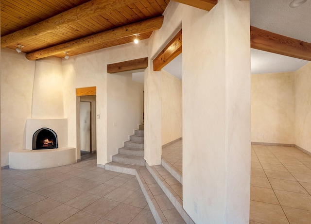 interior space featuring wood ceiling, a large fireplace, beamed ceiling, and light tile patterned flooring