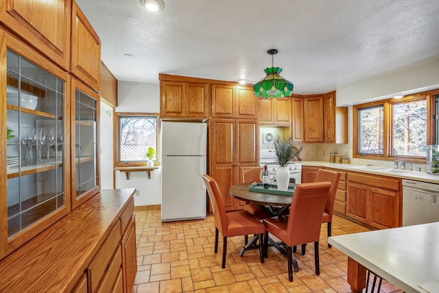 kitchen featuring sink, white appliances, decorative light fixtures, and a textured ceiling