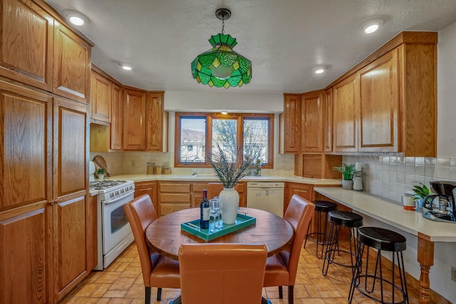 kitchen featuring white appliances, a textured ceiling, hanging light fixtures, and backsplash