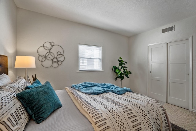 carpeted bedroom with a textured ceiling and a closet