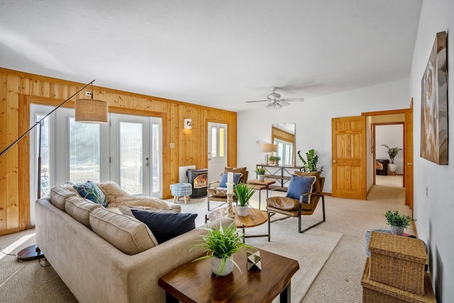 living room with ceiling fan, light colored carpet, and wooden walls