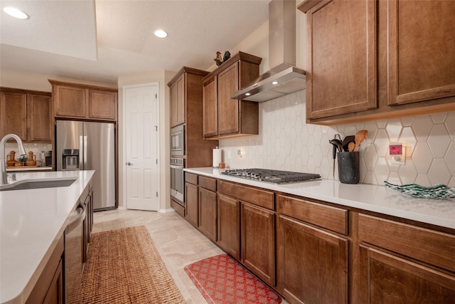 kitchen with appliances with stainless steel finishes, wall chimney exhaust hood, sink, and backsplash