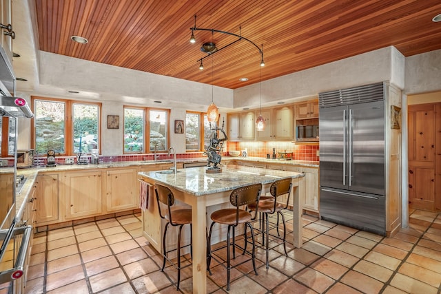 kitchen featuring stainless steel appliances, an island with sink, light stone countertops, and wooden ceiling