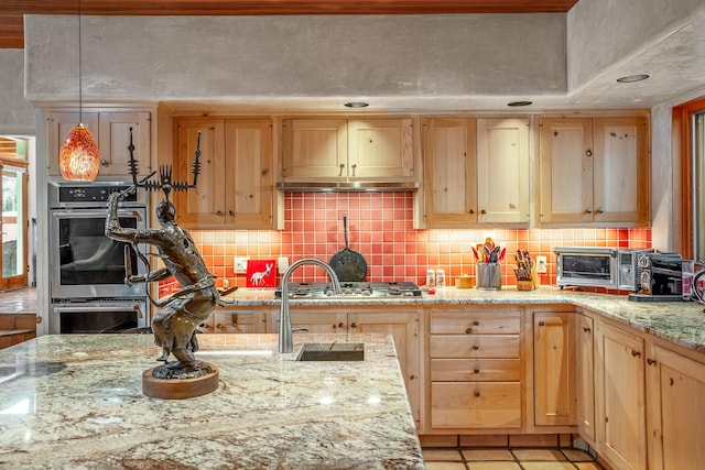 kitchen with light stone counters, stainless steel appliances, hanging light fixtures, and light brown cabinets