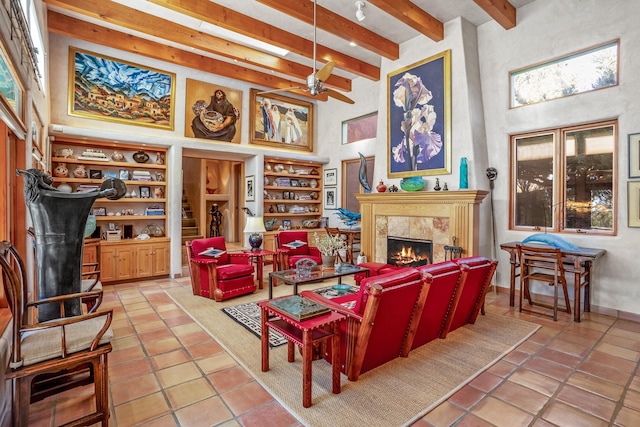 living room featuring a towering ceiling, a fireplace, beamed ceiling, tile patterned flooring, and ceiling fan