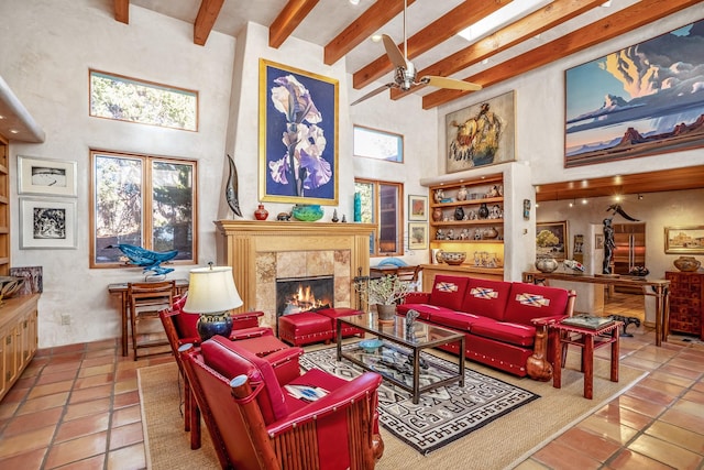 tiled living room featuring ceiling fan, a towering ceiling, beam ceiling, and a tile fireplace