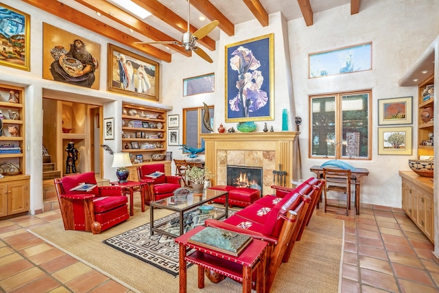 living area featuring built in features, a tile fireplace, beamed ceiling, and a high ceiling