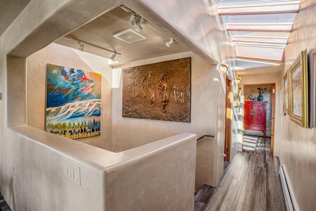 hallway featuring hardwood / wood-style floors, rail lighting, and baseboard heating