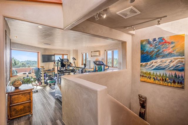 interior space with track lighting, hardwood / wood-style floors, and an AC wall unit