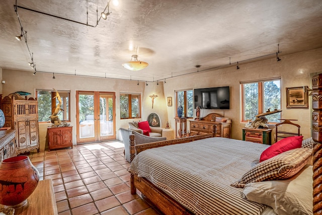 bedroom featuring french doors, access to exterior, light tile patterned flooring, and rail lighting