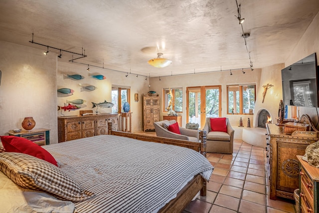 tiled bedroom featuring multiple windows, track lighting, and french doors